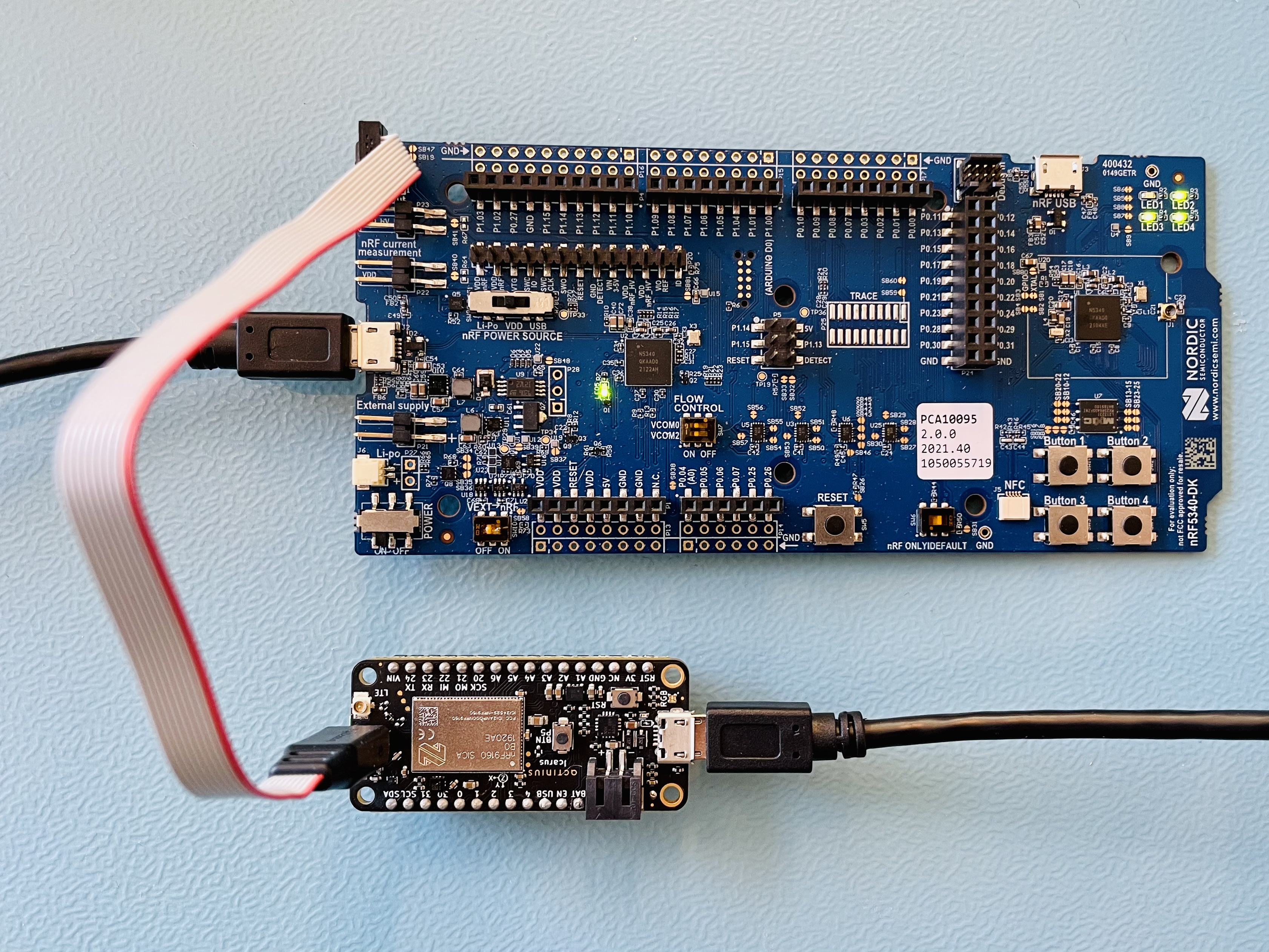 Programming setup with a nRF5340 development kit as a programmer. The boards are connected through the TagConnect cable and are powered through the microUSB ports.